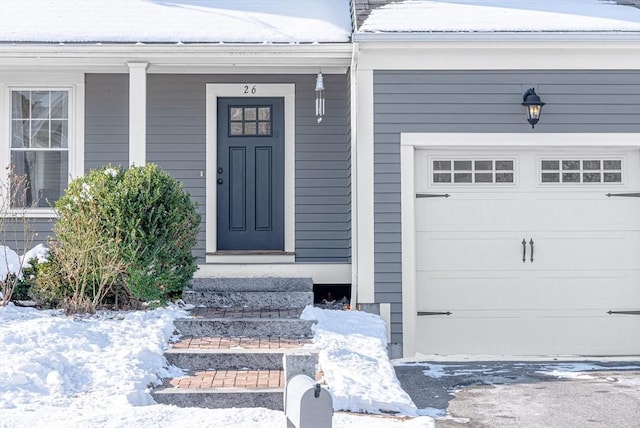 snow covered property entrance with a garage