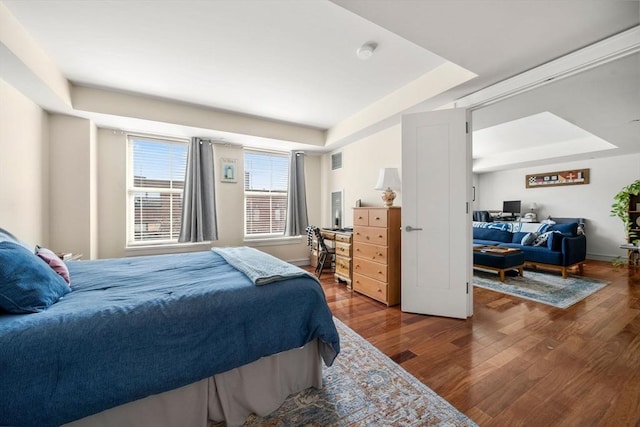 bedroom with a tray ceiling and wood finished floors