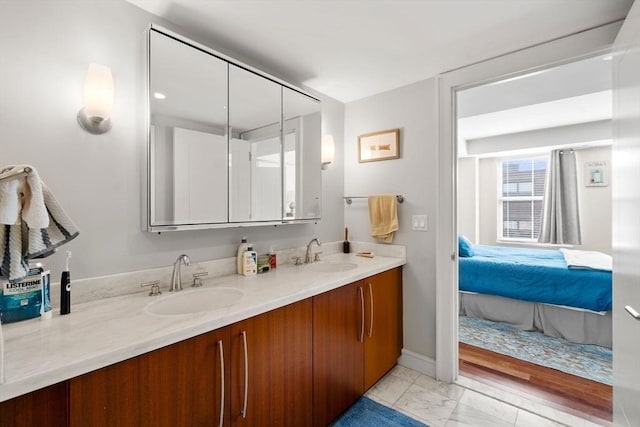 ensuite bathroom featuring connected bathroom, a sink, marble finish floor, and double vanity