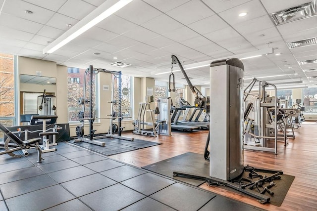 workout area with visible vents, a paneled ceiling, and wood finished floors
