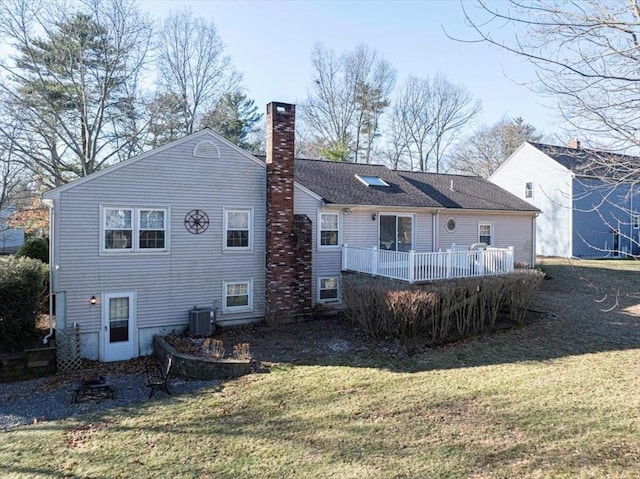 back of property with central AC unit, a wooden deck, and a lawn