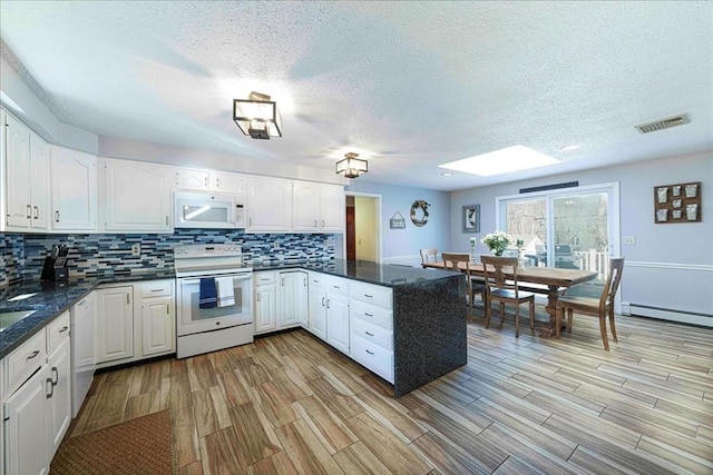 kitchen featuring white appliances, a skylight, white cabinets, and kitchen peninsula