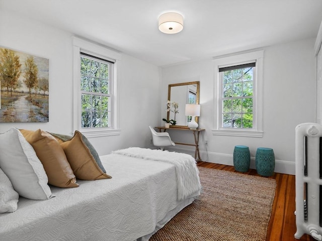 bedroom with baseboards, wood finished floors, and multiple windows