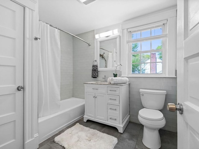 full bath featuring tile patterned flooring, vanity, toilet, shower / bathtub combination with curtain, and tile walls