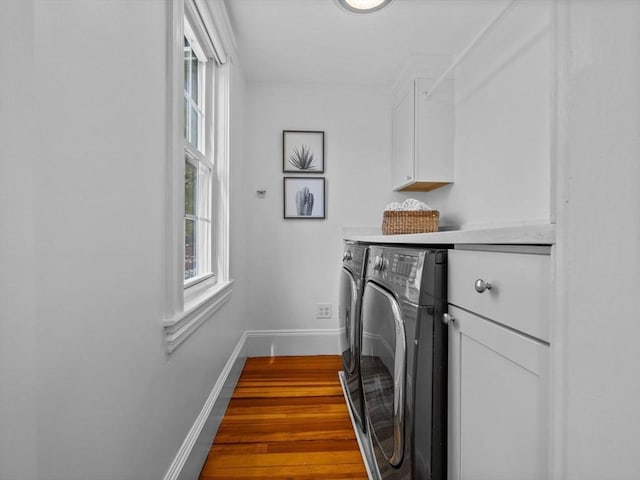 clothes washing area featuring baseboards, cabinet space, dark wood-type flooring, and washing machine and dryer