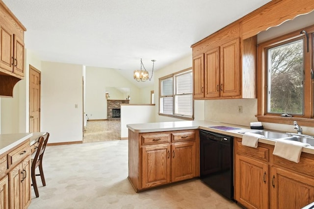kitchen featuring a brick fireplace, a peninsula, light countertops, a sink, and dishwasher