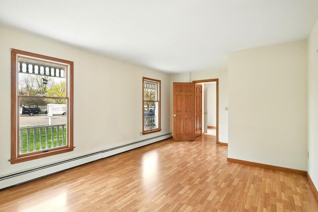 spare room featuring baseboards, a healthy amount of sunlight, light wood-style flooring, and a baseboard radiator