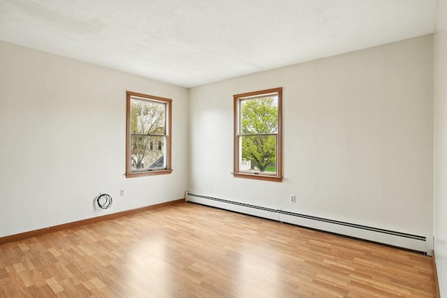 unfurnished room with baseboards, baseboard heating, and light wood-type flooring