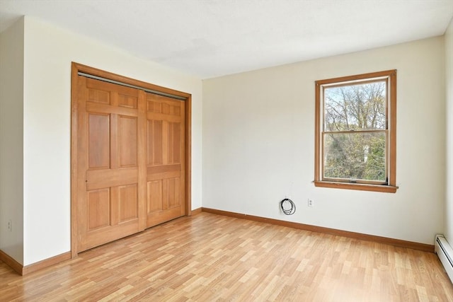 unfurnished bedroom with baseboards, light wood-style flooring, and a baseboard radiator