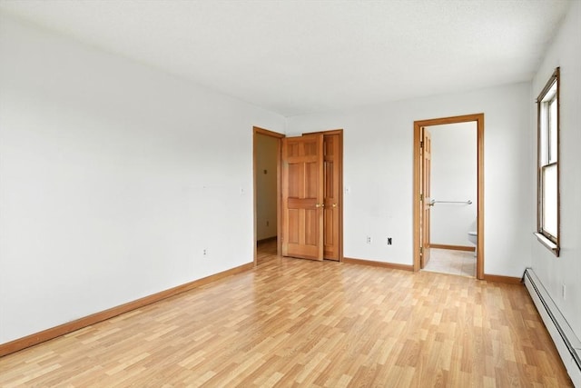 unfurnished bedroom featuring baseboards, a baseboard radiator, multiple windows, and light wood finished floors