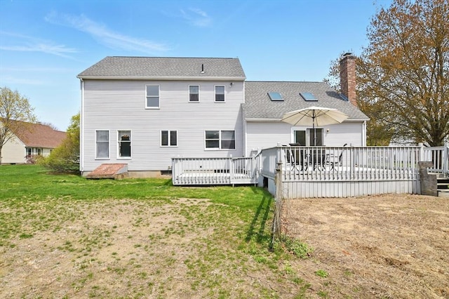 back of property featuring a lawn, a chimney, and a wooden deck