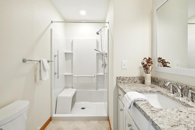full bathroom with toilet, baseboards, a shower stall, and vanity