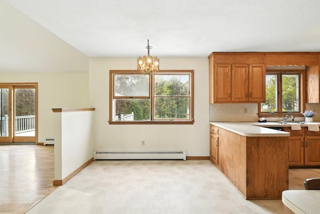 kitchen with brown cabinetry, light countertops, plenty of natural light, and baseboard heating