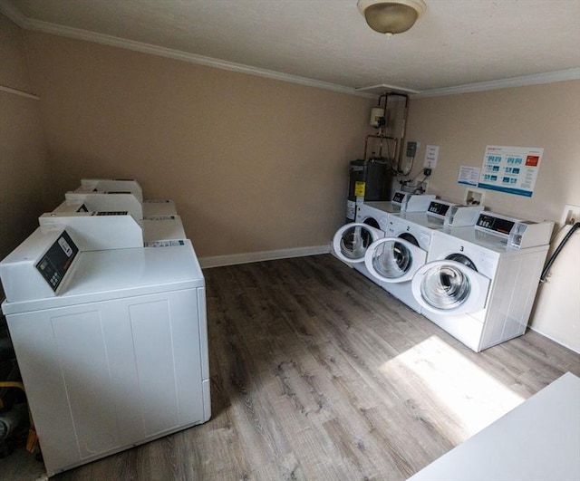 washroom featuring hardwood / wood-style flooring, washing machine and clothes dryer, ornamental molding, and water heater