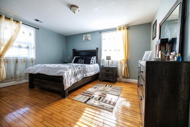 bedroom featuring a baseboard heating unit, a textured ceiling, and light wood-type flooring