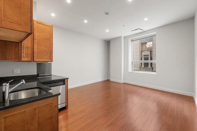 kitchen featuring stainless steel dishwasher, sink, and light hardwood / wood-style flooring