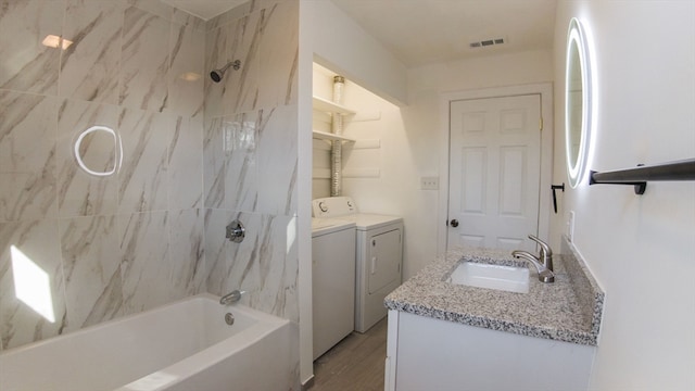 bathroom with separate washer and dryer, vanity, wood-type flooring, and tiled shower / bath combo