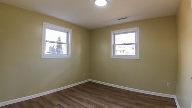 empty room featuring plenty of natural light and dark hardwood / wood-style floors