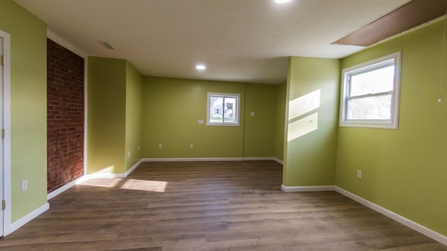 spare room featuring brick wall and hardwood / wood-style flooring