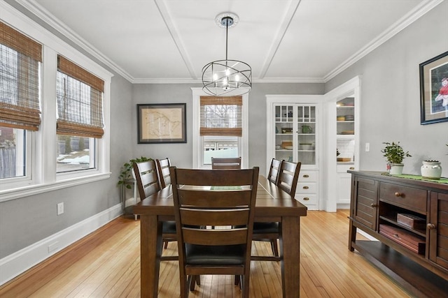 dining room featuring light wood-style floors, ornamental molding, baseboards, and an inviting chandelier