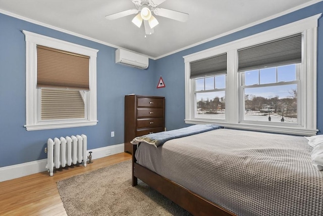 bedroom with crown molding, radiator heating unit, an AC wall unit, wood finished floors, and baseboards