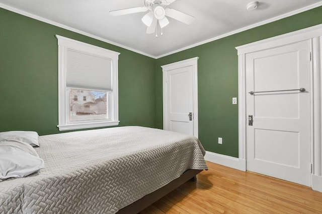 bedroom with ornamental molding, ceiling fan, light wood finished floors, and baseboards