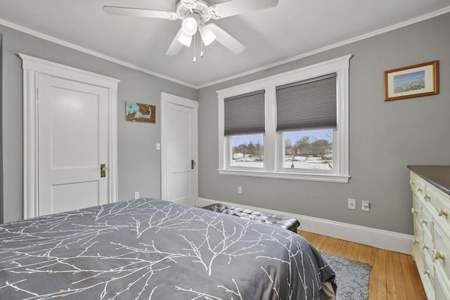 bedroom featuring a ceiling fan, baseboards, crown molding, and wood finished floors