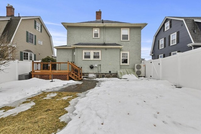 snow covered rear of property with a gambrel roof, a fenced backyard, and a wooden deck