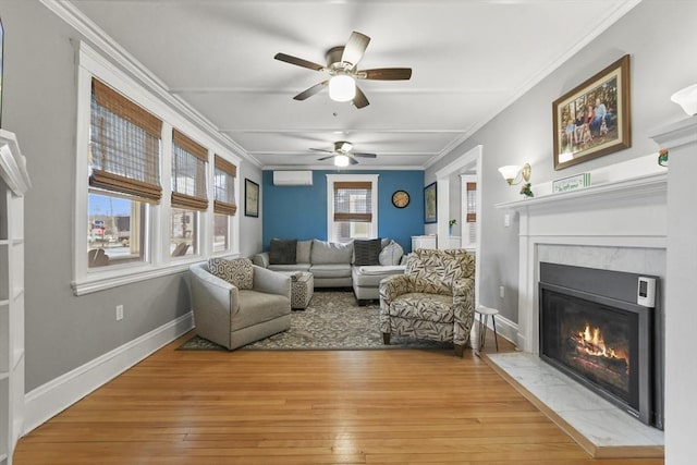 sitting room with a fireplace with flush hearth, baseboards, light wood-style floors, an AC wall unit, and ornamental molding