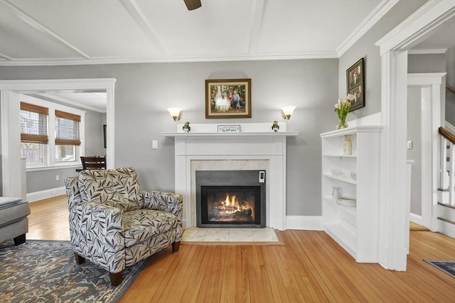 living room with a fireplace with flush hearth, ornamental molding, wood finished floors, and baseboards