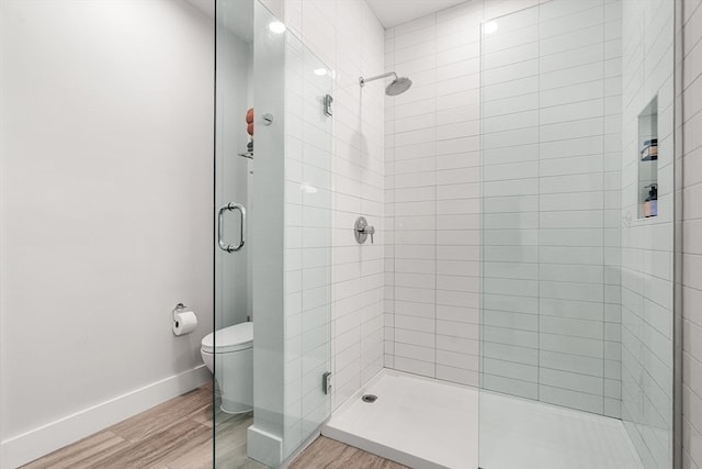 bathroom featuring wood-type flooring, a shower with door, and toilet