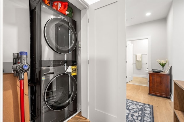 clothes washing area with light hardwood / wood-style floors and stacked washer / drying machine