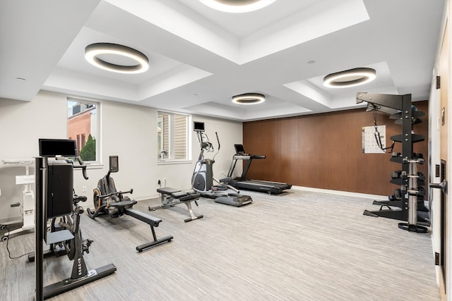 gym with carpet floors, a raised ceiling, and wood walls