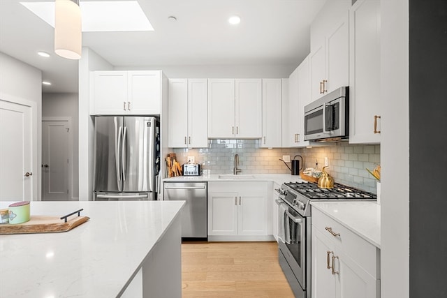 kitchen featuring light hardwood / wood-style flooring, appliances with stainless steel finishes, and white cabinetry