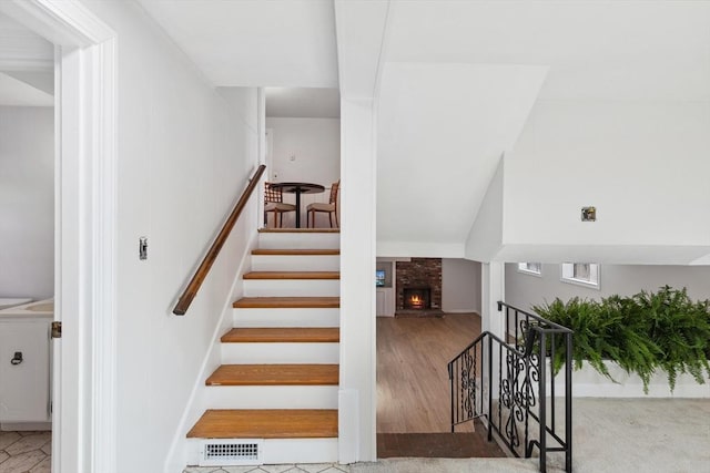 stairs featuring visible vents, a fireplace, and wood finished floors