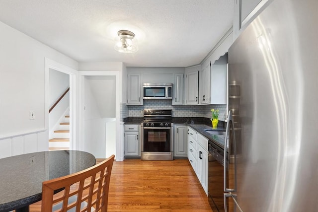 kitchen featuring dark countertops, gray cabinets, light wood finished floors, and stainless steel appliances