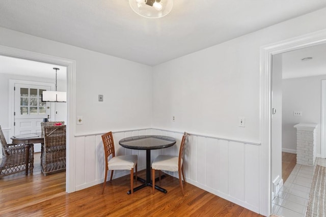 dining space featuring wood finished floors and a wainscoted wall