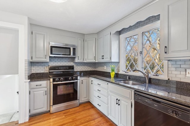 kitchen featuring electric stove, a sink, stainless steel microwave, light wood finished floors, and dishwasher