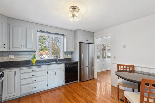 kitchen with a sink, plenty of natural light, dark countertops, and appliances with stainless steel finishes