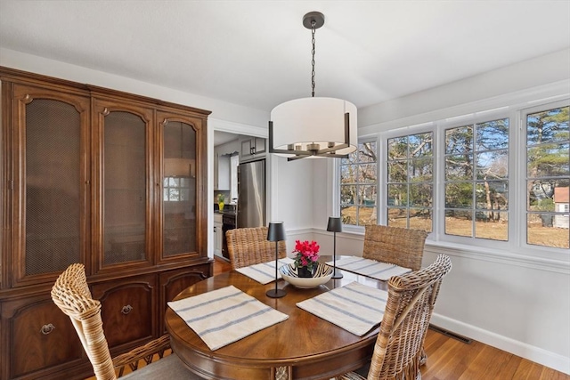 dining area featuring visible vents, baseboards, and wood finished floors