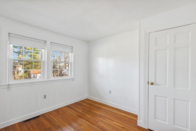 spare room featuring baseboards, visible vents, and wood-type flooring