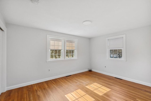 empty room featuring visible vents, light wood-style flooring, and baseboards