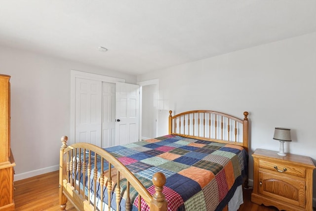 bedroom with light wood-style flooring, baseboards, and a closet