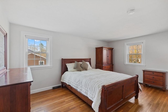 bedroom featuring multiple windows, baseboards, and light wood-style floors