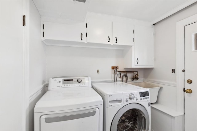 laundry area featuring washing machine and dryer, cabinet space, and a sink