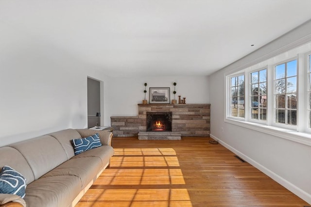 living area with a fireplace, light wood-style floors, and baseboards