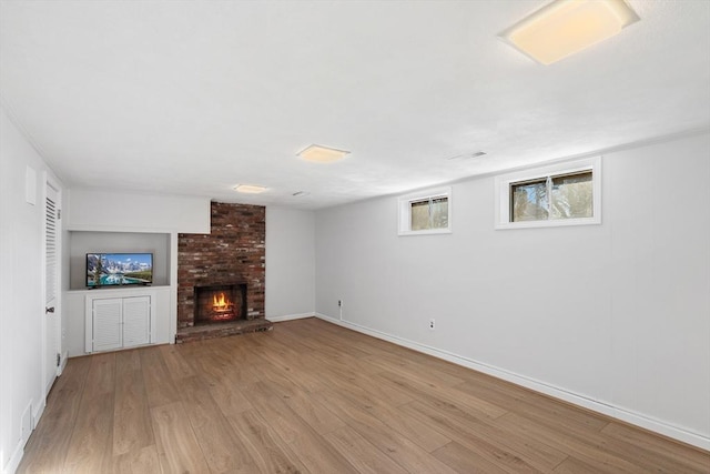 unfurnished living room featuring baseboards, a brick fireplace, and wood finished floors