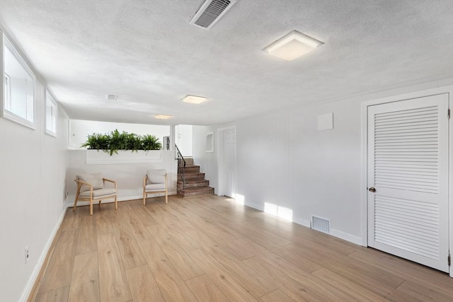 unfurnished room featuring visible vents, a textured ceiling, and light wood-type flooring