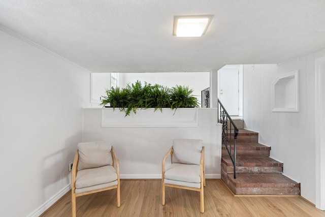 sitting room with stairway, wood finished floors, and baseboards