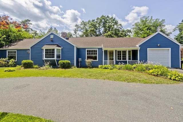 ranch-style home featuring a garage, covered porch, and a front lawn